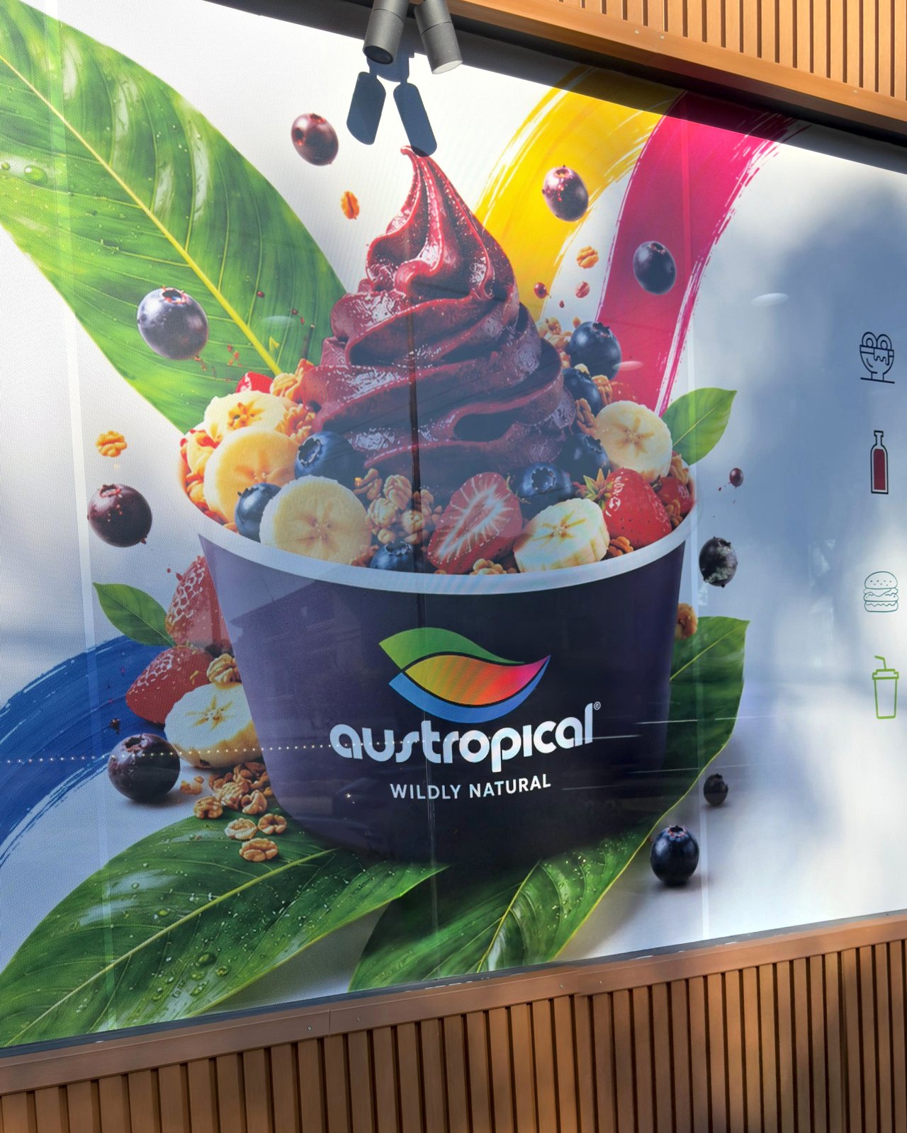 Our original Austropical wall mural: açaí bowl artwork, tropical fruit, saturated color and the brand logo.